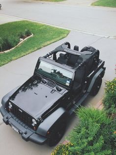 the jeep is parked on the side of the road in front of some bushes and trees