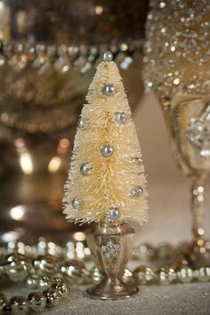 a small white christmas tree sitting on top of a table next to two wine glasses