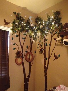 a bedroom decorated with trees, lights and stuffed animals on the wall next to it