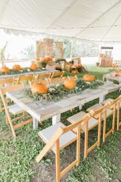 an outdoor table with pumpkins and greenery is set up for a wedding reception