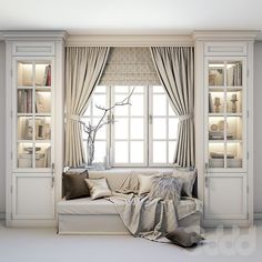 a white couch sitting in front of a window next to a book shelf filled with books