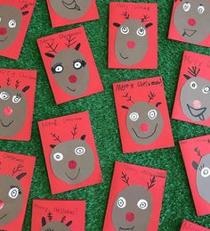 some red cards with reindeer faces on them are laying on the grass and have been made to look like they're ready for christmas