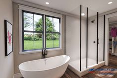 a large white bath tub sitting next to a walk in shower under a bathroom window