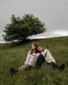 two people laying in the grass near a tree