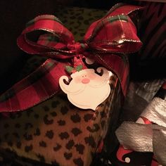 a present wrapped in red and green ribbon with a santa clause tag on it's side