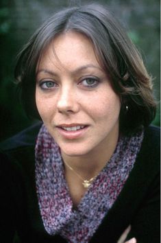 a close up of a person wearing a scarf and posing for a photo with trees in the background