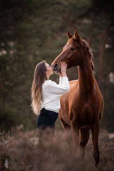 a woman standing next to a brown horse