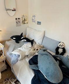 an unmade bed with stuffed animals on it in a small room next to a mirror