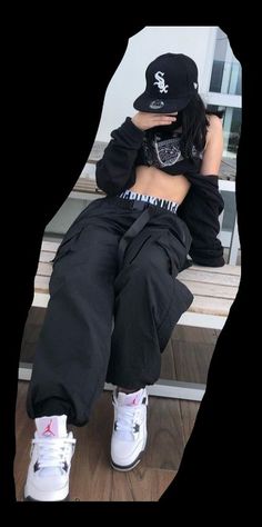 a woman sitting on top of a wooden bench wearing white sneakers and a black hat