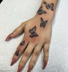 a woman's hand with black butterflies on the left side of her arm and fingers