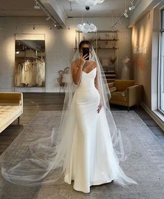 a woman in a white wedding dress is taking a selfie with her cell phone