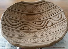 a large bowl sitting on top of a wooden table next to a paper and scissors