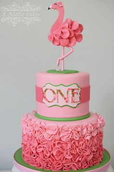 a pink and green cake with a flamingo topper on it's tier