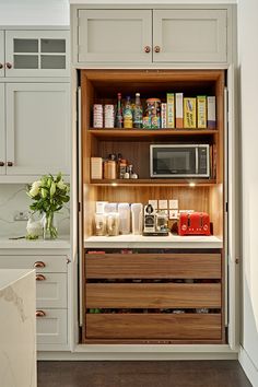 an open cabinet in a kitchen with lots of items on the counter and cupboard doors