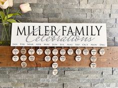 a family celebration sign hanging on a brick wall in front of a vase with flowers