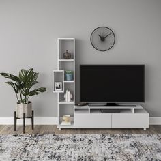 a living room with a large television on top of a white entertainment center next to a potted plant