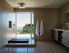 a bathroom with a bench, shower and large window