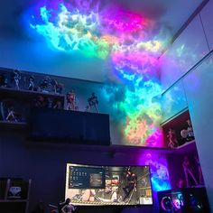 a computer monitor sitting on top of a desk under a rainbow colored cloud filled sky