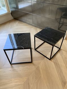 two black tables sitting on top of a wooden floor