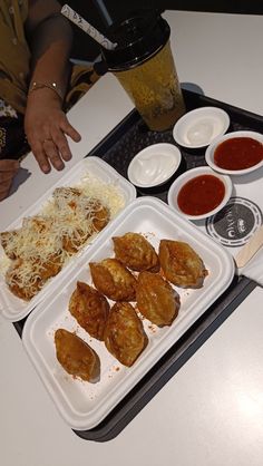 a tray with some food on top of it next to two cups and sauces