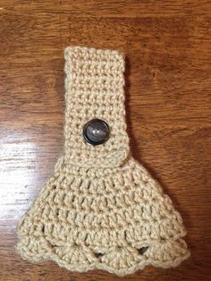 a crocheted object with a button on top of it sitting on a wooden surface