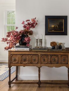 a wooden table with two vases on top of it next to a painting and candles