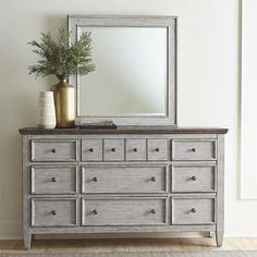 a dresser with a mirror and vase on top