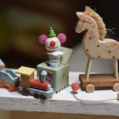 a wooden toy train with a clown riding on the front, and a horse in the back