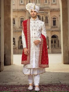 a man dressed in white and red is posing for the camera