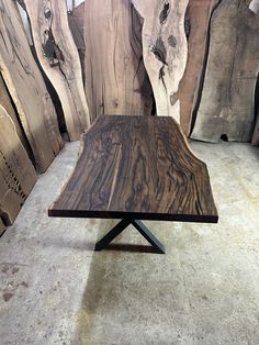 a wooden table sitting on top of a floor next to large slabs of tree trunks