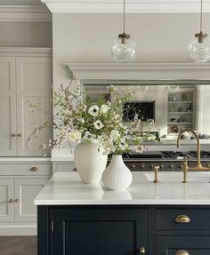 two vases with flowers sit on a kitchen island