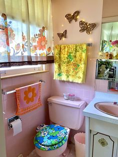 a bathroom with pink walls and colorful decorations on the window sill above the toilet