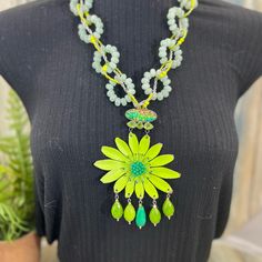 a woman wearing a necklace with green and yellow beads on it, including a flower