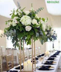 there is a tall centerpiece with white flowers on it and candles in the middle