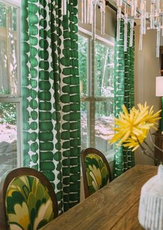 a dining room with green curtains and yellow flowers