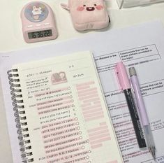 an open notebook sitting on top of a desk next to a calculator and pen