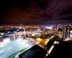 an aerial view of a city at night with the lights on and buildings lit up