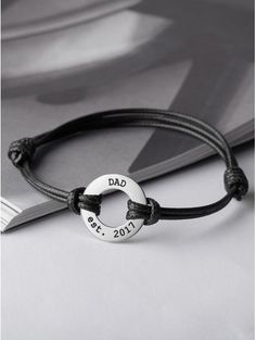 a black leather bracelet with the word dad on it and a circle in the middle