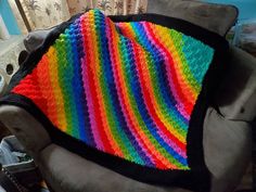 a multicolored crocheted blanket sitting on top of a chair