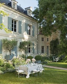 a table and chairs in front of a large house