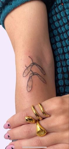 a woman's hand with two gold rings on it and a tattoo design on the wrist