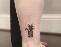 a black cat tattoo on the ankle is shown in front of a woman's leg