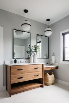 a bathroom with two sinks and mirrors on the wall next to a basket full of flowers