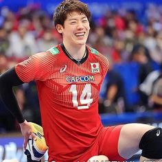 a young man is playing volleyball in front of an audience and smiling at the camera