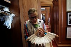 a woman is looking at an old fashioned crochet piece on a hanger