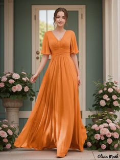 a woman standing in front of a door wearing an orange dress with short sleeves and pleaed skirt