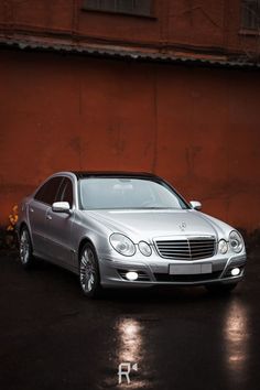 a silver car parked in front of a red wall