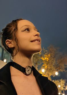 a woman wearing a black leather jacket looking up at the sky with her eyes closed