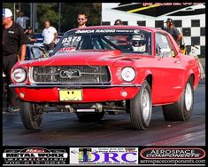 an old red mustang car driving on a race track