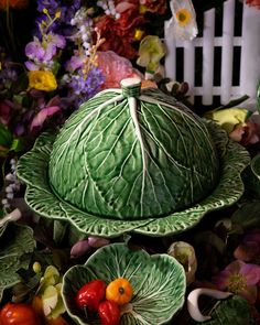 there is a large cabbage bowl and two small bowls on the ground with flowers in the background